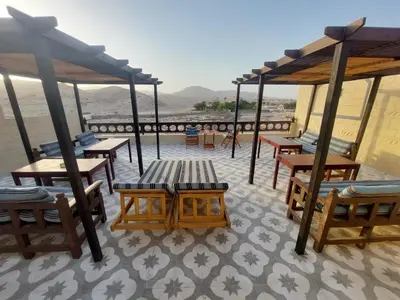 a patio with tables and benches on a roof at Carter Guesthouse Luxor 4 in ‘Ezbet Abu Ḥabashi