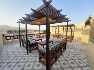 a patio with benches and tables on a roof at Carter Guesthouse Luxor 4 in ‘Ezbet Abu Ḥabashi