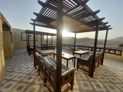 a pavilion with benches and tables and a view of the mountains at Carter Guesthouse Luxor 4 in ‘Ezbet Abu Ḥabashi
