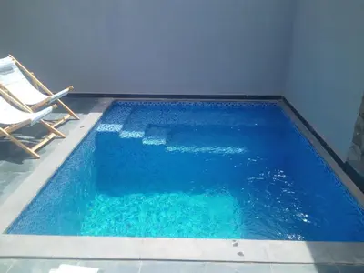 a swimming pool with two chairs and blue water at Gouna Retreat with Private Pool in Bali in Hurghada