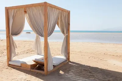 a canopy bed on the beach near the water at Beachfront Somabay Cabana Steps From Sea & Pool in Hurghada