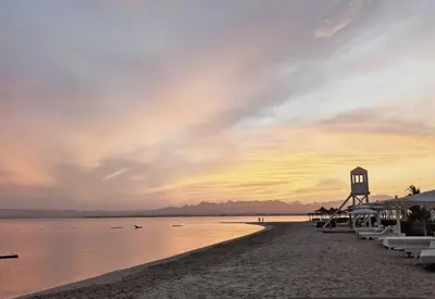 a beach with umbrellas and the ocean at sunset at Beachfront Somabay Cabana Steps From Sea & Pool in Hurghada