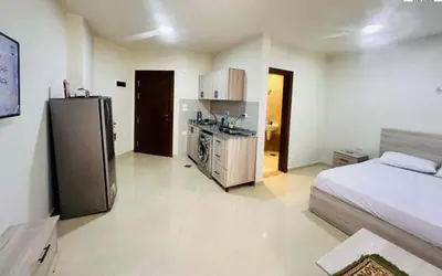 a room with a bed and a kitchen with a refrigerator at Zuni in Hurghada