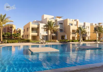 a large swimming pool with palm trees and buildings at Mangroovy Retreat Smart home in Hurghada