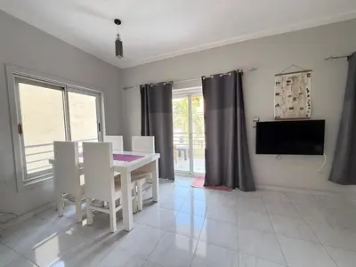 a dining room with a table and chairs and a tv at Nile Spirit Apt 2 in Jazīrat al ‘Awwāmīyah