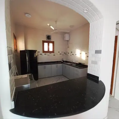 a large kitchen with a black refrigerator and white cabinets at Christine Home in Luxor