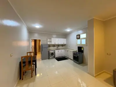 a kitchen with white cabinets and a table and a stove at The Nile Paradise in Al Aqālitah