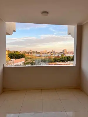 a large window in a room with a view of a city at The Nile Paradise in Al Aqālitah