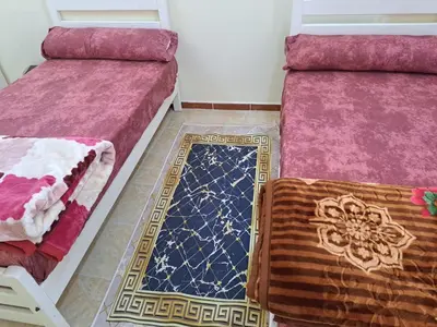 a room with two beds and a rug on the floor at Sweet Home 8 in Hurghada