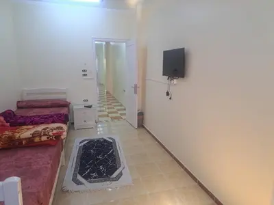 a room with two beds and a flat screen tv at Sweet Home 8 in Hurghada