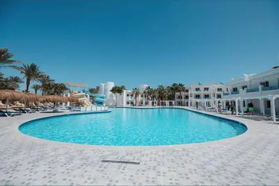 a swimming pool in a resort with chairs and palm trees at Veronia gad chalet Mirage bay aqua park in Hurghada