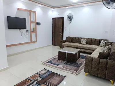 a living room with a couch and a tv at شقة كاملة بغرفتي نوم دور ارضي in Hurghada