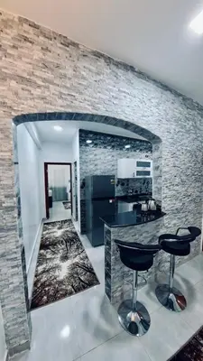 a kitchen with a counter and two bar stools at Al Mansi Luxury Retreat in Jazīrat al ‘Awwāmīyah