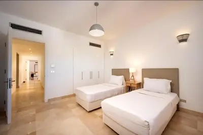 two beds in a room with white walls and wooden floors at Luxury Stays in New Marina El Gouna in Hurghada
