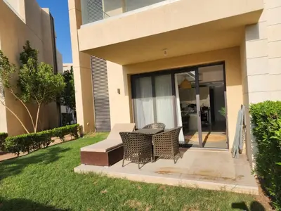 a patio with two chairs and a table in a yard at El Gouna Poolfront Cozy Stay 2BR in Hurghada
