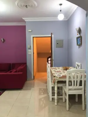 a dining room with a table and a red couch at Ozera villa - west bank in Luxor