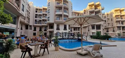 a hotel with a pool and tables and an umbrella at Apartmant for family in Hurghada in Hurghada