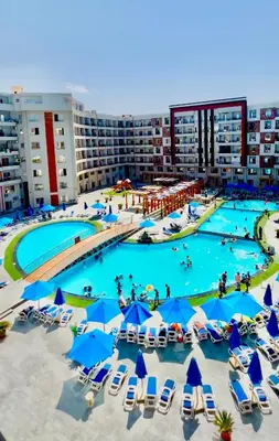 an aerial view of a large pool with chairs and umbrellas at طيبة جولد Tiba Gold in Hurghada