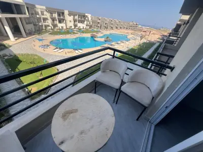 a balcony with two chairs and a table and a pool at Panorama View Sahl Hashesh Luxury Suite in Hurghada