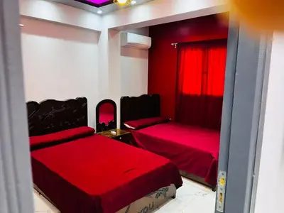 a red room with two beds and a window at شقه في ميدان العروسه in Hurghada