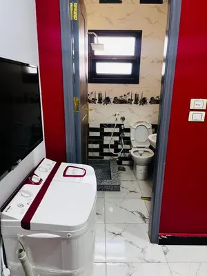 a bathroom with a toilet and a red wall at شقه في ميدان العروسه in Hurghada