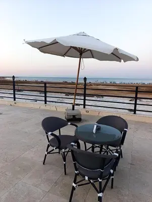 a table and chairs with an umbrella next to the ocean at Oasis marina in Hurghada