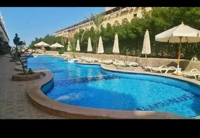 a large swimming pool with chairs and umbrellas at كمبوند كابتن in Hurghada