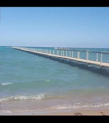 a long pier in the ocean with a beach at كمبوند كابتن in Hurghada