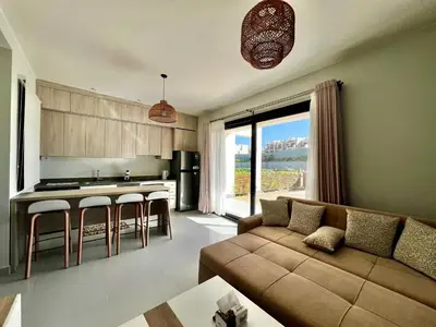 a living room with a couch and a kitchen at Makadi Heights Luxury 1-BR App with Garden & Lagoon View in Hurghada