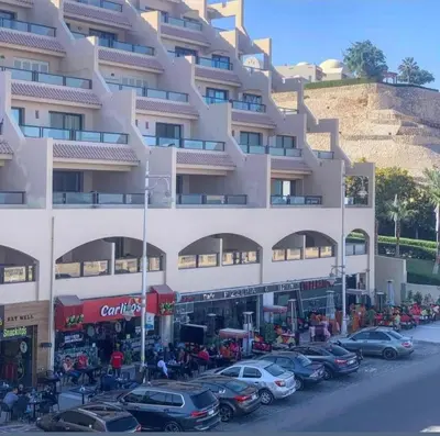 a large white building with cars parked in a parking lot at The view in Hurghada