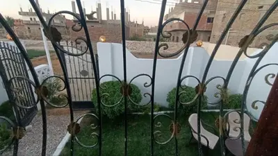 an iron gate with a garden behind it at Relaxing Lodge in Luxor in ‘Ezbet Abu Ḥabashi