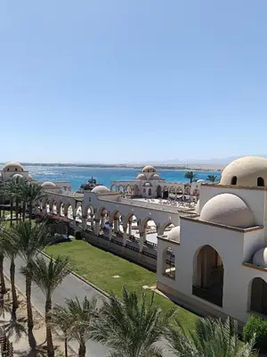 a view of a building with palm trees and the ocean at EDElma in Hurghada