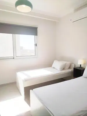 a white room with two beds and a window at Bay breeze in Hurghada