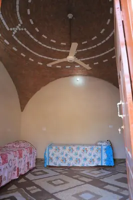 a room with two beds and a ceiling at House of Tranquility in Al Aqālitah