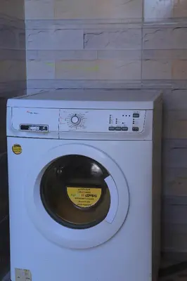 a white washing machine with a yellow label on it at House of Tranquility in Al Aqālitah