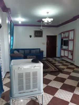a living room with a blue couch and a fan at Blue Sky Apartments & Restaurant in Luxor