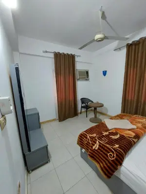 a bedroom with a bed and a chair in it at Blue Sky Apartments & Restaurant in Luxor