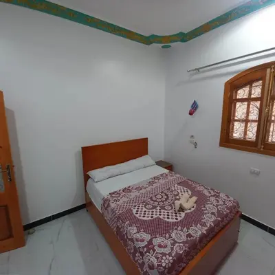 a bedroom with a bed with a red bedspread and a window at Villa Nicole in Luxor