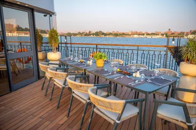 a table and chairs on a deck with a view of the water at Sonesta Dahabeya Amirat II - Nile Cruise Ship From Luxor to Aswan 4 nights in Luxor
