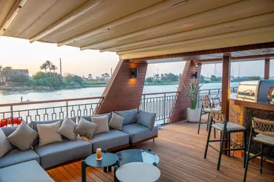 a balcony with a couch and a view of a river at Sonesta Dahabeya Amirat II - Nile Cruise Ship From Luxor to Aswan 4 nights in Luxor
