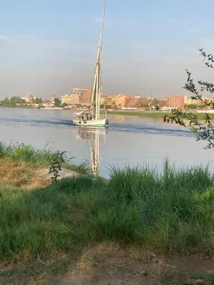 a sail boat on a river with a city in the background at Elbess For Toursim in Luxor