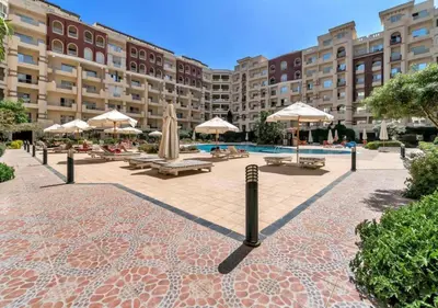 a courtyard with tables and umbrellas and a pool at Cozy Studio in Hurghada in Hurghada