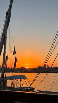 a boat in the water with the sunset in the background at Luxor temple view in Luxor