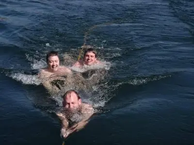 three men are swimming in the water at Taha nubian boat in Jazīrat Aswān