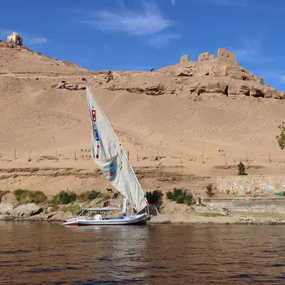 a small boat with a sail in the water at Taha nubian boat in Jazīrat Aswān