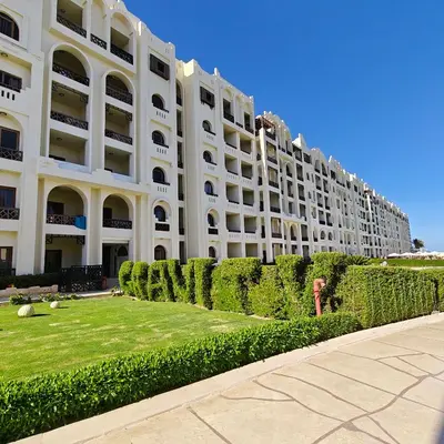 a large white building with a hedge in front of it at Sahl Hasheesh Aparthotel Beachfront - SAHLHOMES in Hurghada