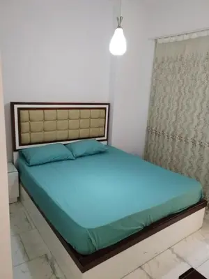 a bedroom with a bed with blue sheets and a window at Hurghada Seafront Family Apartment with Pool View in Hurghada
