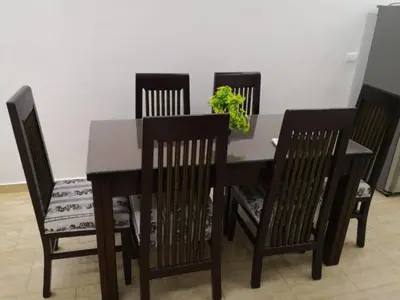 a dining room table with four chairs and a plant at Hurghada Seafront Family Apartment with Pool View in Hurghada