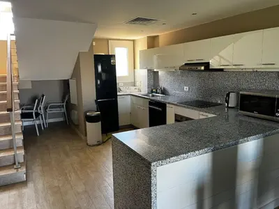 a kitchen with white cabinets and a black refrigerator at El Gouna Joubal Villa #2 with Private Garden and Lagoon View in El Gouna