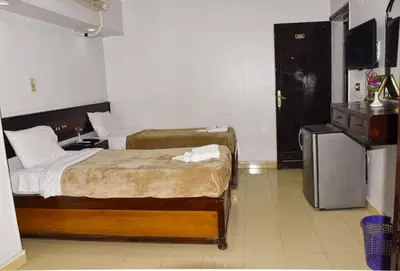 a bedroom with two beds and a dresser in it at Oscar Hotel Aswan \u4e2d\u570b\u4eba\u4e4b\u5bb6 in Aswan